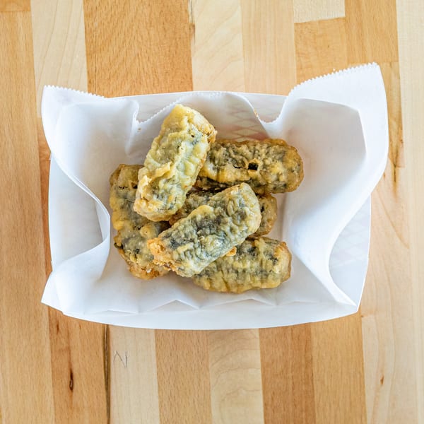 Several fried seaweed rolls, or gim-mari, in a white paper tray on a wooden table.